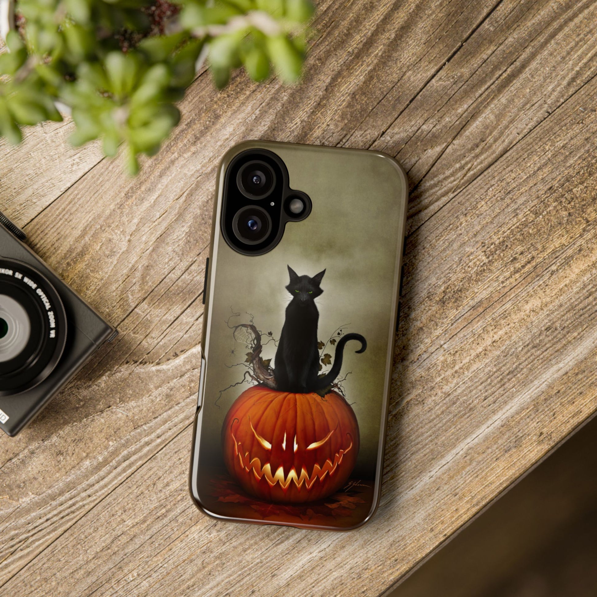 Cat O' Lantern Halloween phone case on phone laying on table — dark art by Mister Sam Shearon
